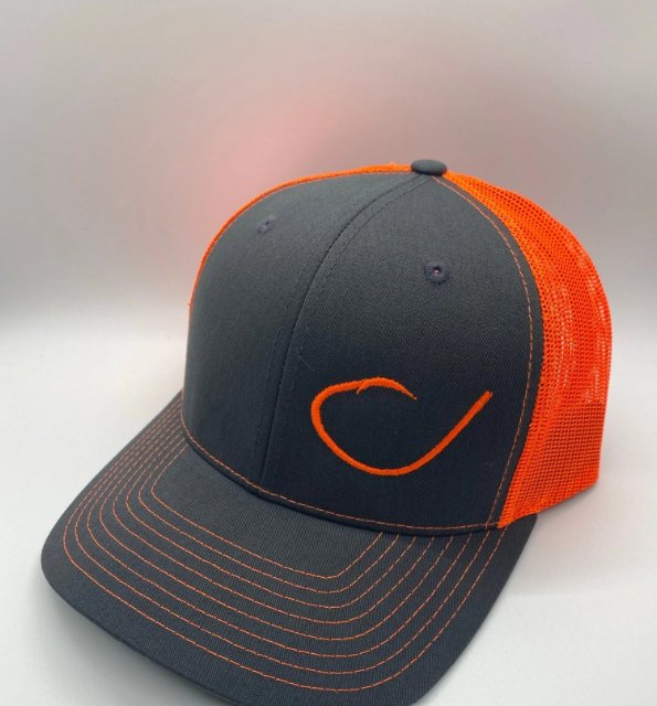 A cap on a white floor next to a white wall. The cap has a gray front with an image of an orange fish hook on it.