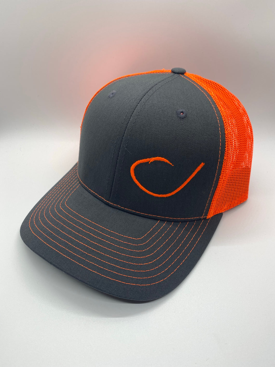 Charcoal and neon orange mesh trucker hat with a round fish hook on the front from Swamp Cracker Outdoor Apparel. 